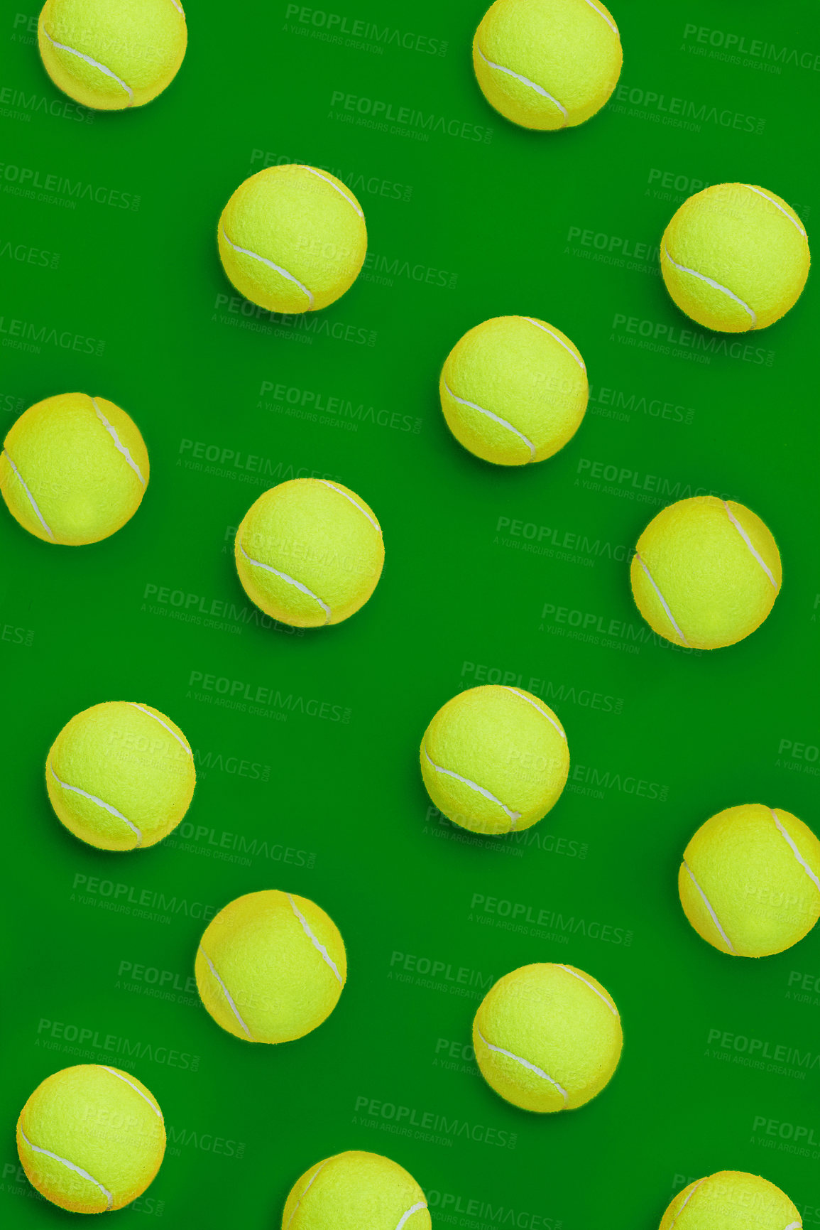 Buy stock photo High angle shot of a group of tennis balls placed together in formation on top of a green background inside of a studio
