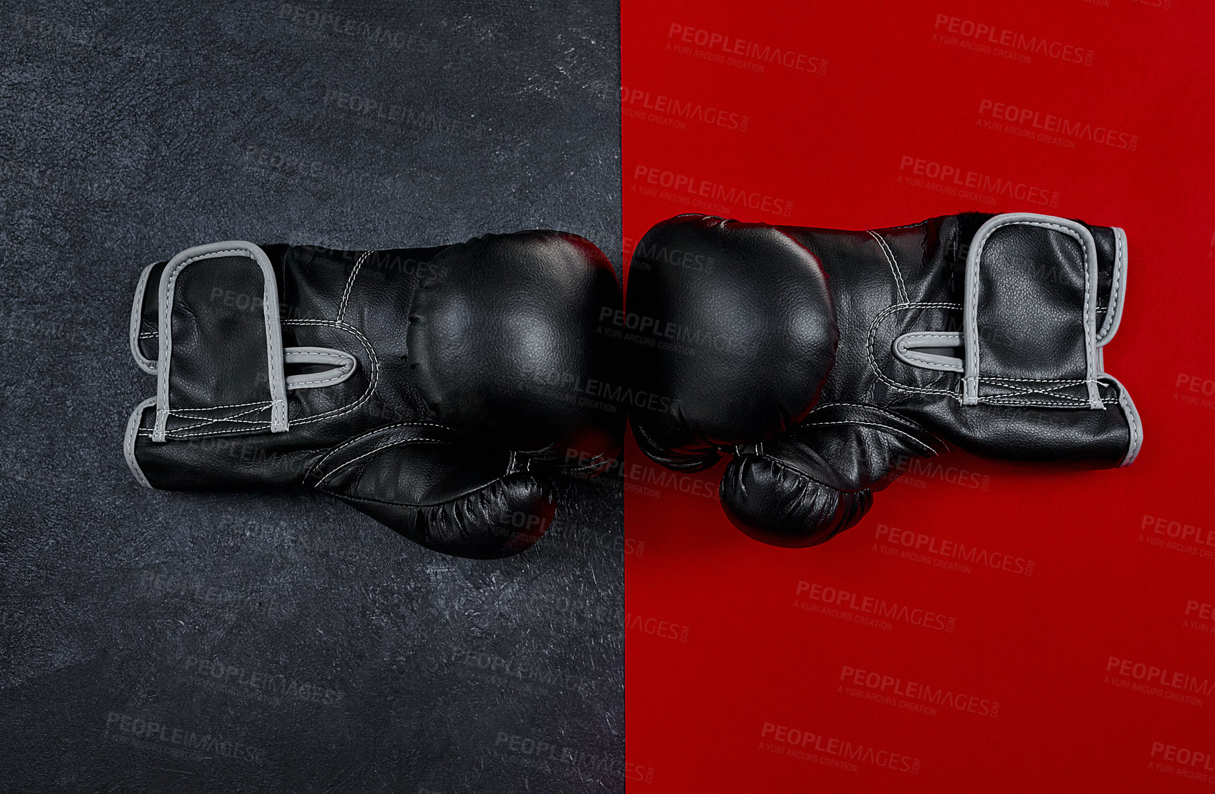 Buy stock photo High angle shot of a pair of boxing gloves placed together on top of a multi coloured background inside of a studio