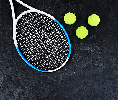 Buy stock photo High angle shot of a single tennis racket and a few tennis balls placed on a dark background inside of a studio