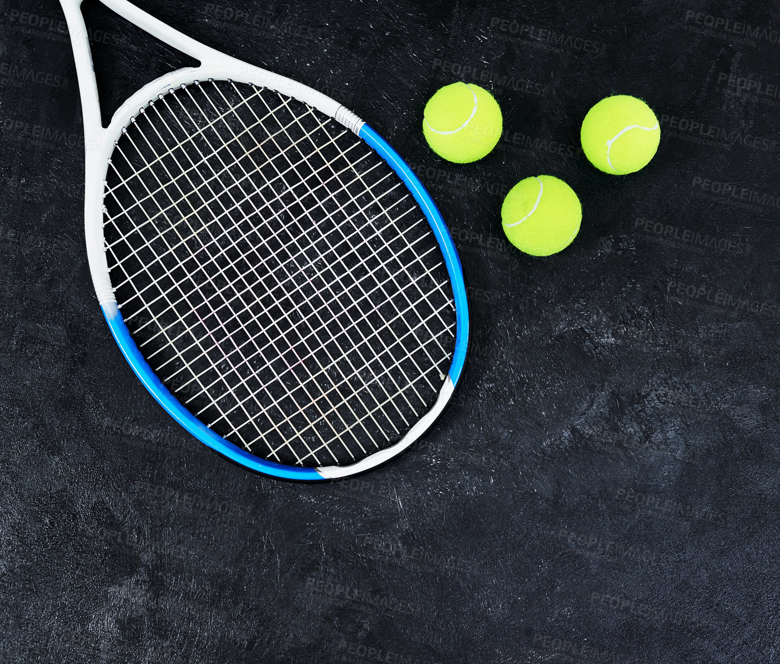 Buy stock photo High angle shot of a single tennis racket and a few tennis balls placed on a dark background inside of a studio