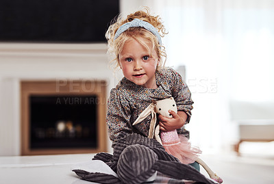 Buy stock photo Cropped portrait of an adorable little girl standing alone in the living room and playing with her toys at home