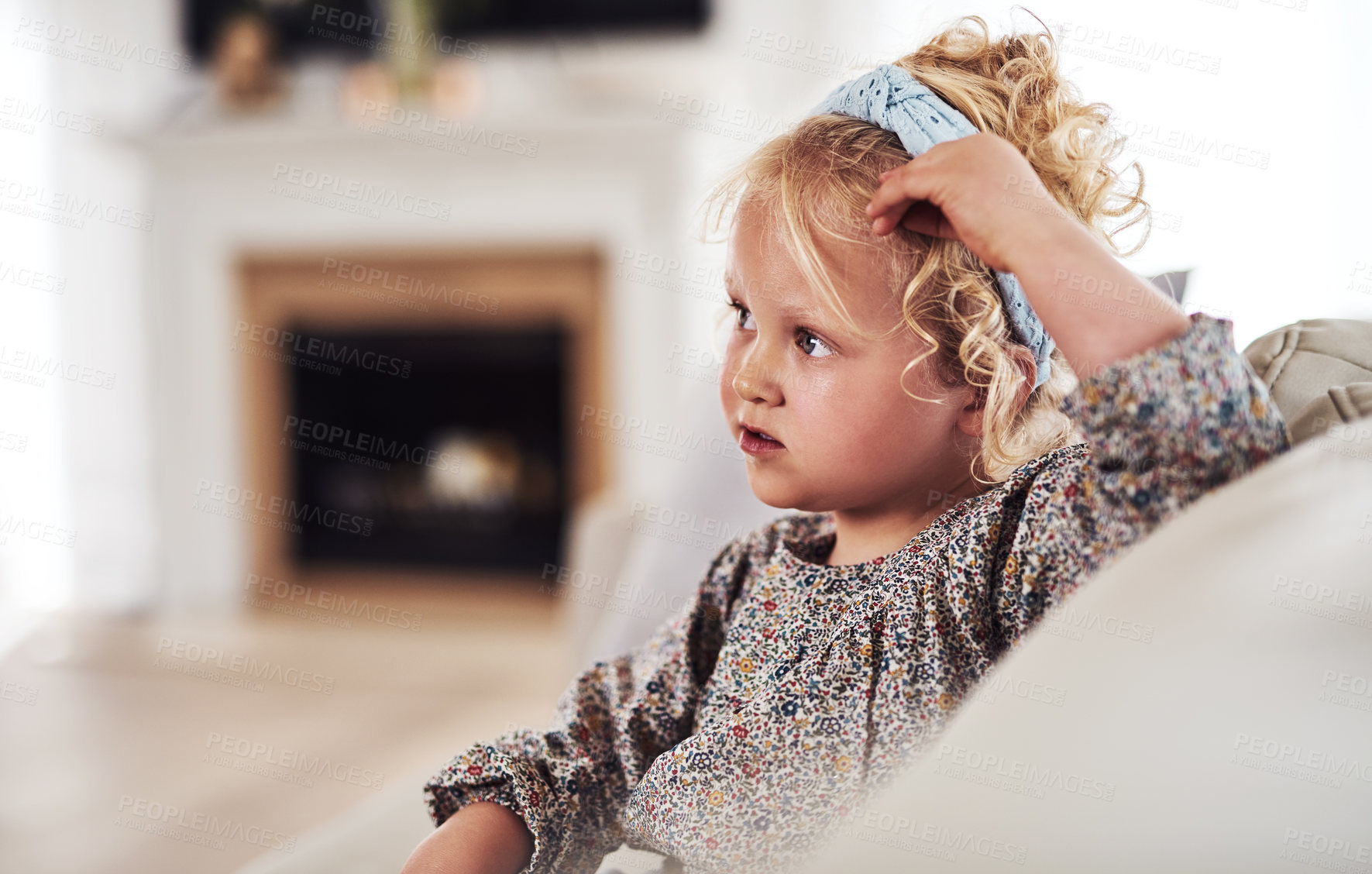 Buy stock photo Cropped shot of an adorable little girl sitting alone on the sofa during a day at home