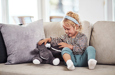 Buy stock photo Full length shot of an adorable little girl sitting alone on the sofa and playing with her toys at home