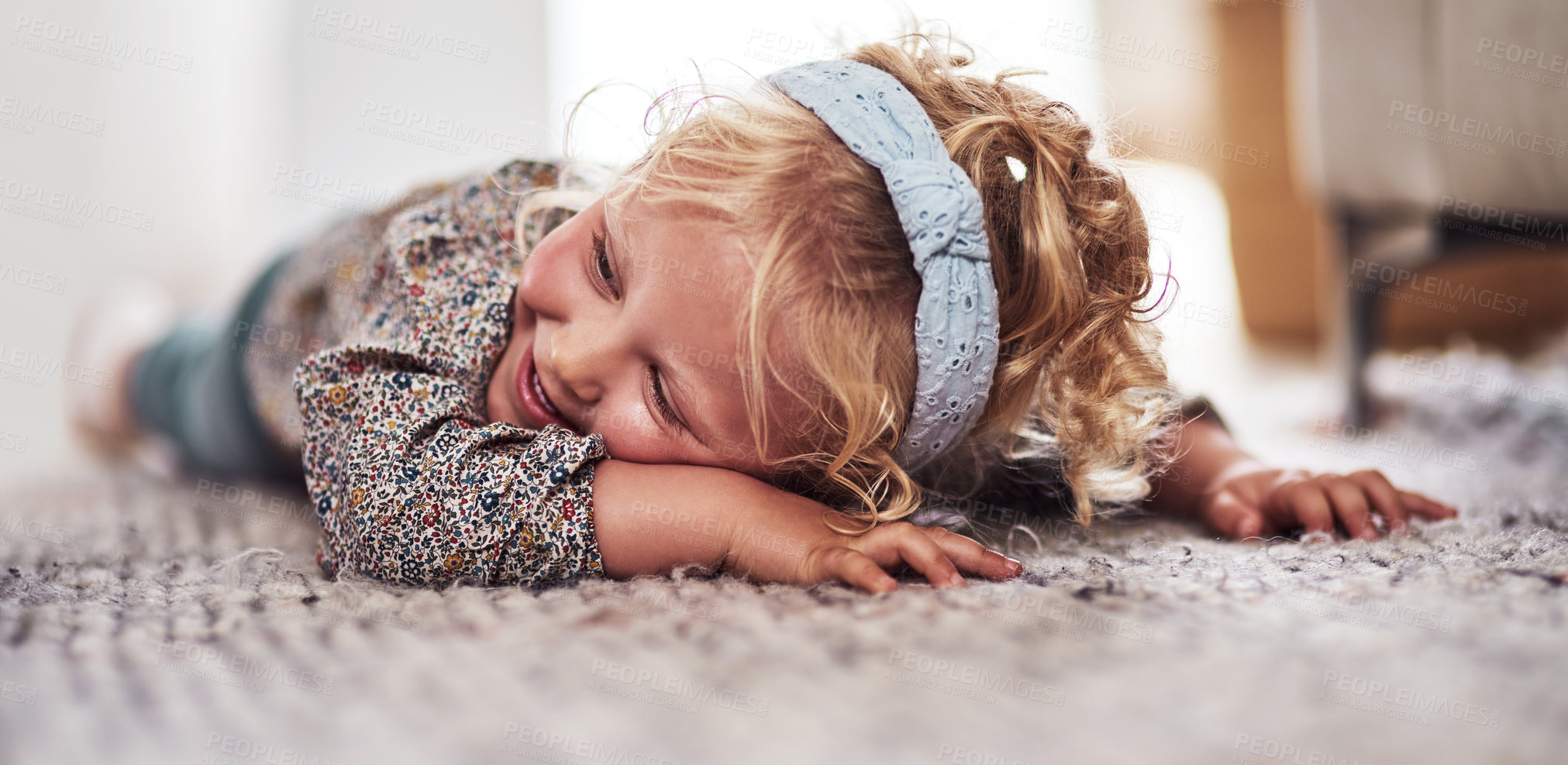 Buy stock photo Cropped shot of an adorable little girl lying alone on the living room floor at home