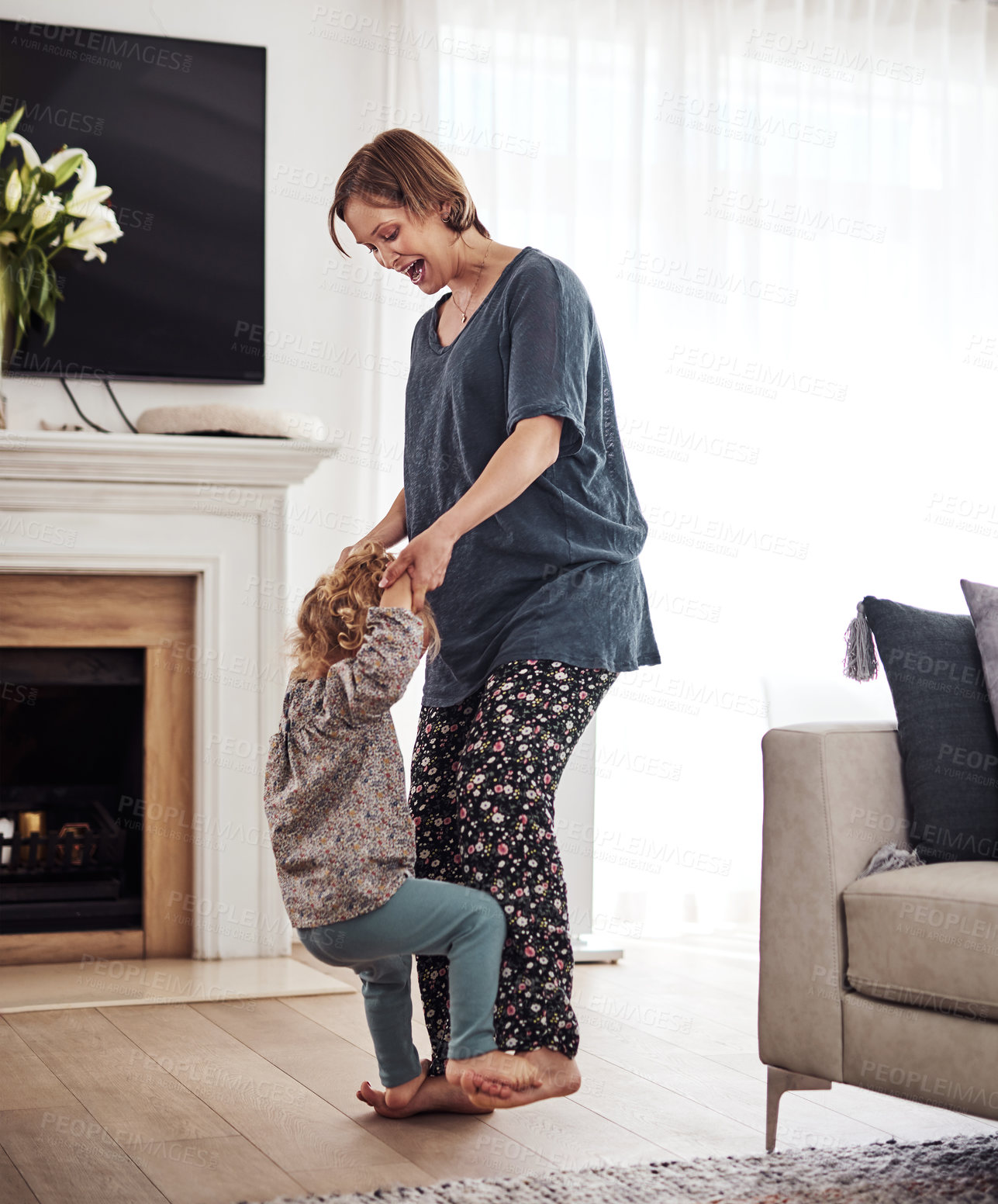 Buy stock photo Full length shot of an attractive young mother and dancing with her daughter in the living room at home