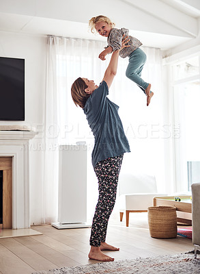 Buy stock photo Full length shot of an attractive young mother and playing with her daughter in the living room at home