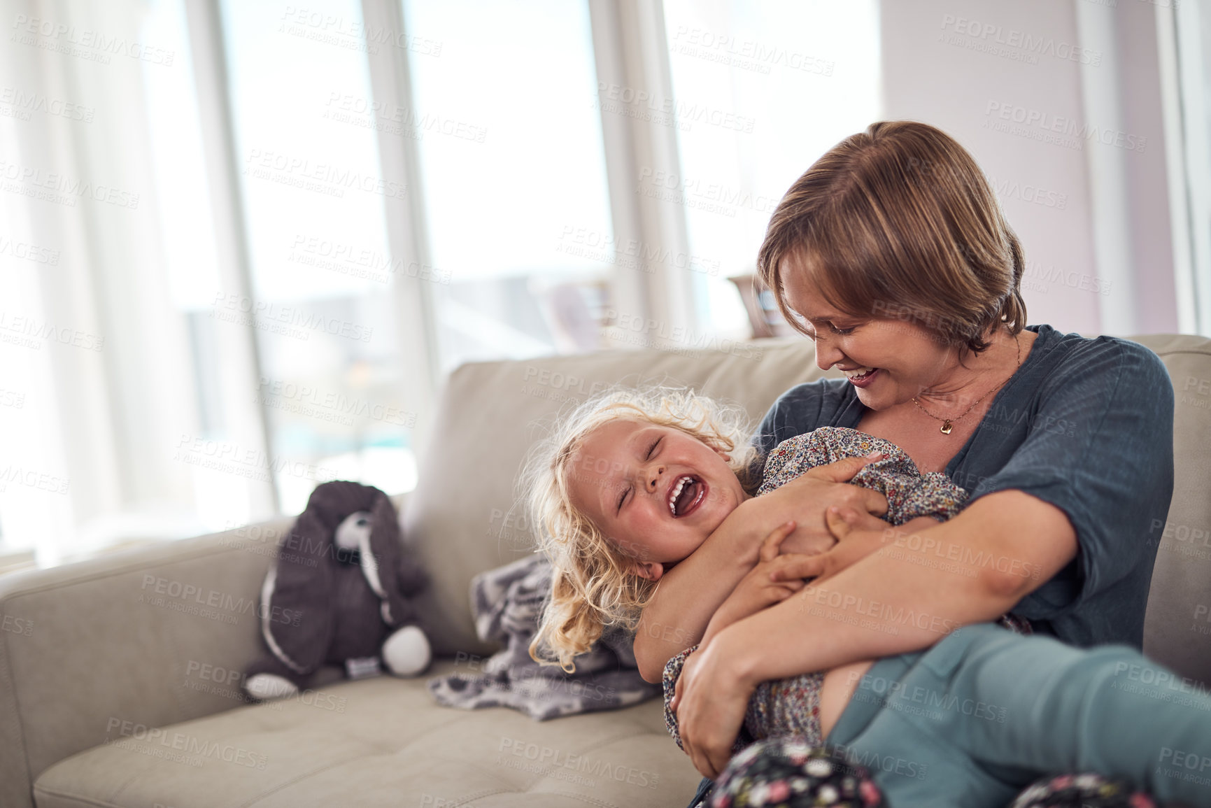 Buy stock photo Cropped shot of an attractive young mother sitting on the sofa and hugging her daughter at home