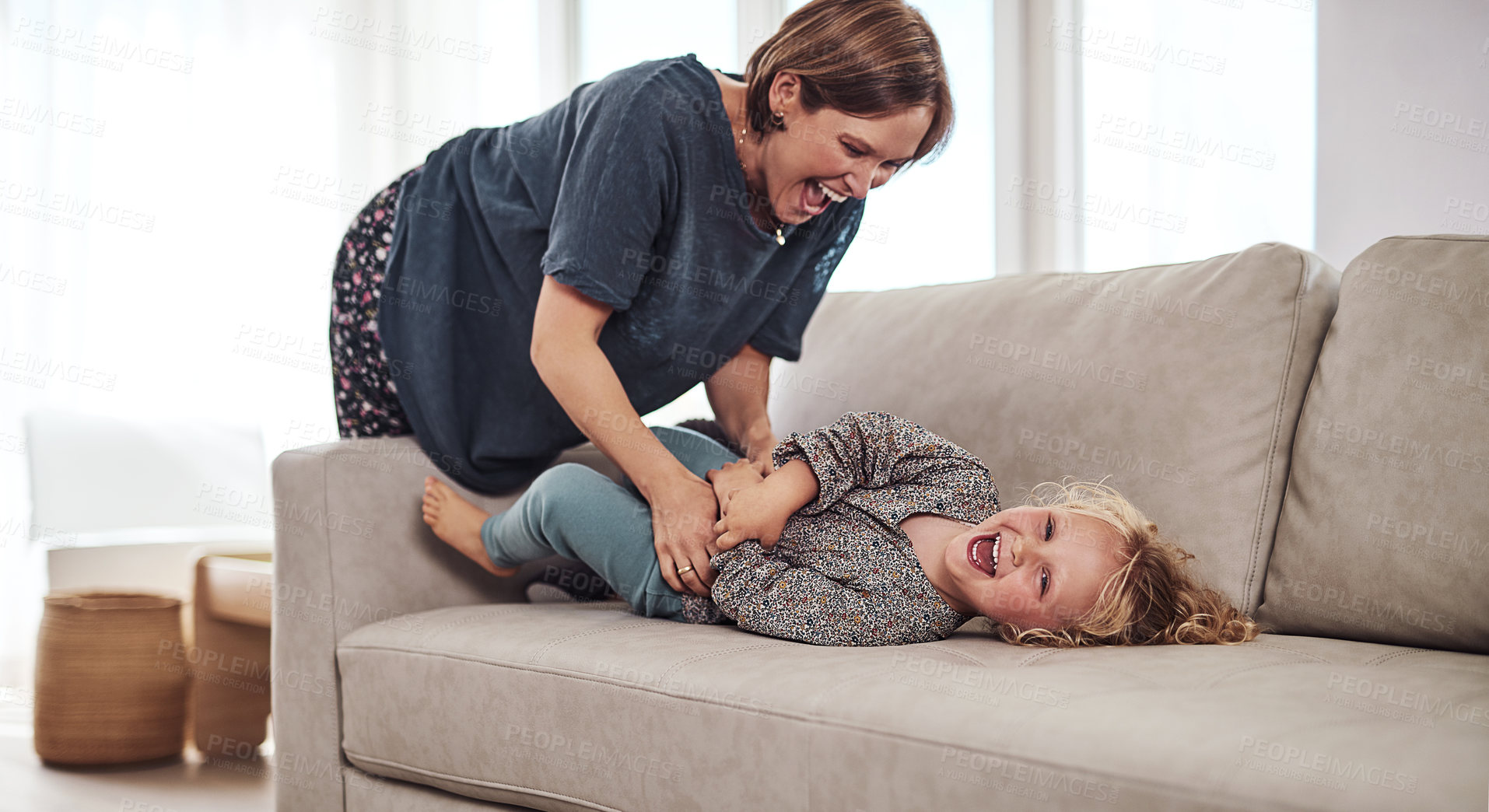 Buy stock photo Girl, tickle and mother on sofa for fun, bonding and childhood development in living room with happy mood. Female child, family and playful in house for laugh, games and joy with mom, love and care