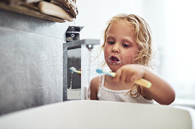 Buy stock photo Cropped shot of an adorable little girl standing alone and brushing her teeth during her morning routine at home