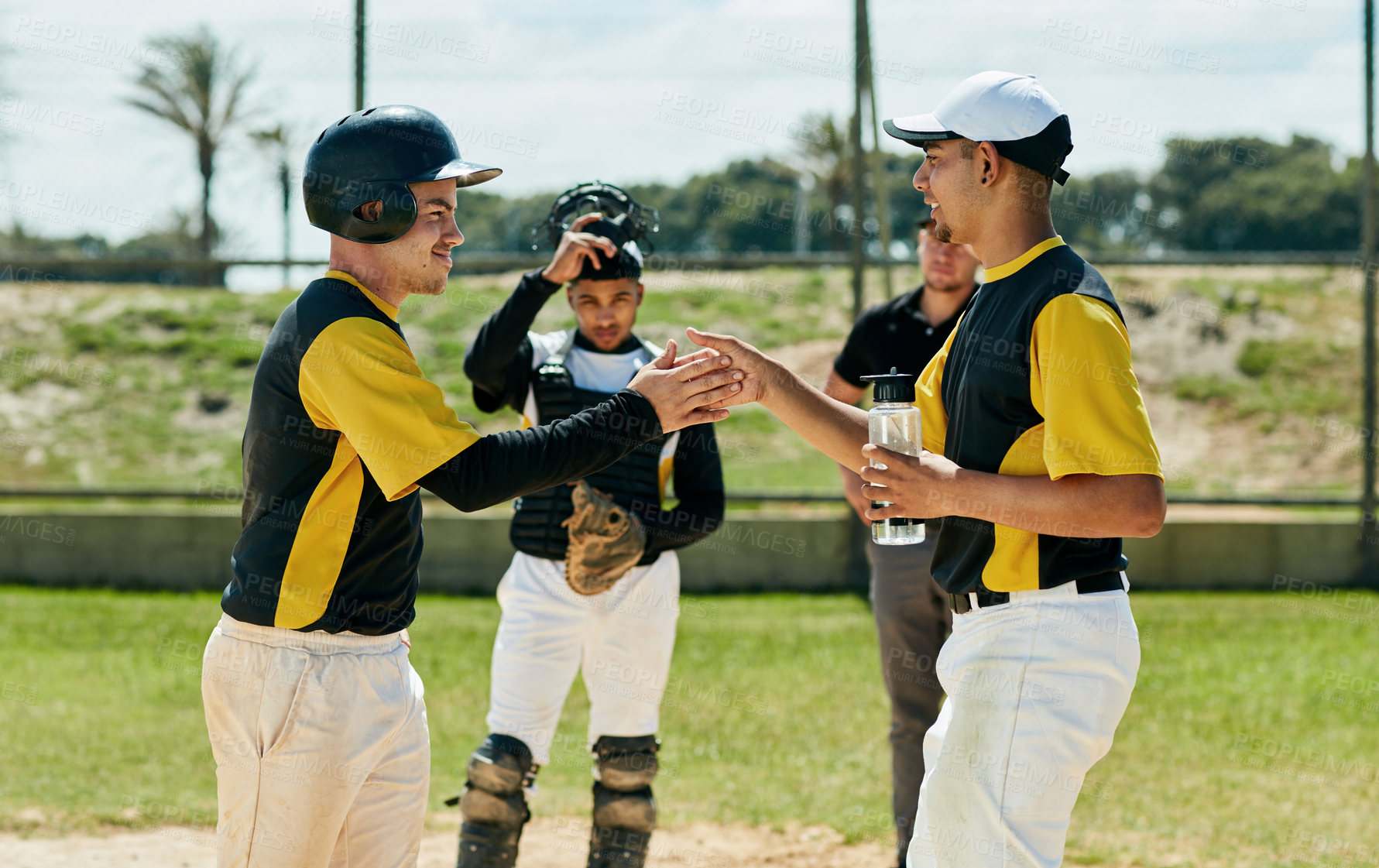 Buy stock photo Cropped shot of two handsome young baseball players cheering while standing on the field during the day