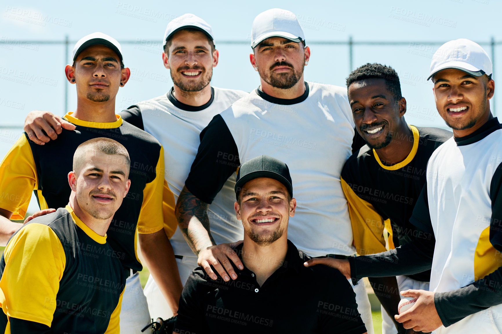 Buy stock photo Cropped portrait of a team of handsome young baseball players smiling while standing on  the field during the day