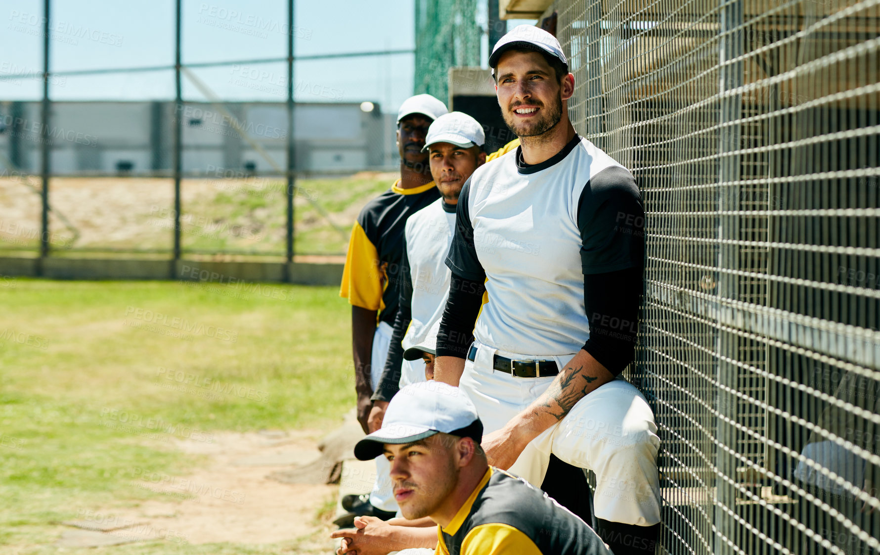 Buy stock photo Cropped shot of a group of young baseball players watching a game near a baseball field during the day