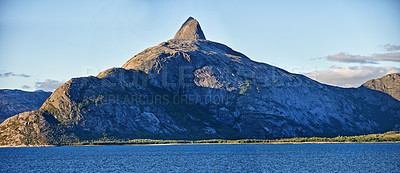 Buy stock photo Scenic view a mountain lining a coast in Bodo, Norway. An expansive natural vista of a spring lake during sunrise in the morning. Remote, lush vegetation alongside a lake in a European destination