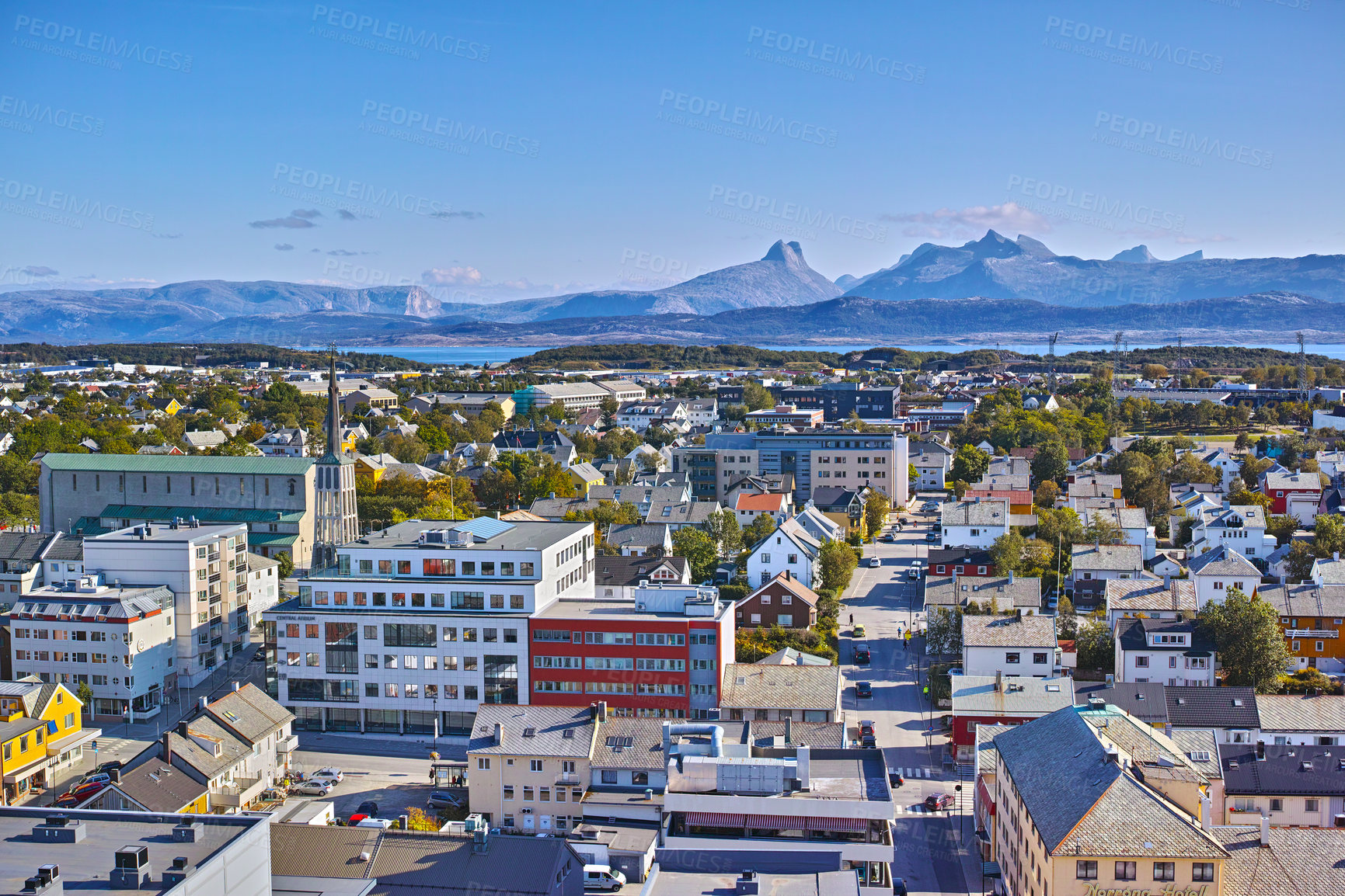 Buy stock photo Aerial view of Bodo city in Norway on a sunny day with a blue sky. Scenic modern urban landscape of streets and buildings near a mountain horizon with copy space. Peaceful rural town from above