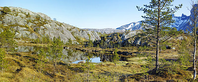 Buy stock photo Lush rocky wilderness with greenery of wild grass and trees surrounding a pond with a blue sky copy space background. Peaceful landscape of empty woodland perfect for exploring nature in Bodo, Noway