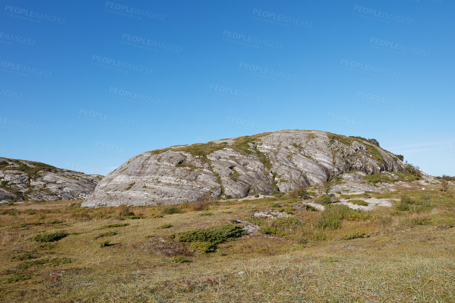 Buy stock photo Scenic landscape of Bodo in Nordland with natural surrounding and blue sky copyspace background. Rock formation on mountain and hill with dry barren plants. Hiking trails in the countryside of Norway