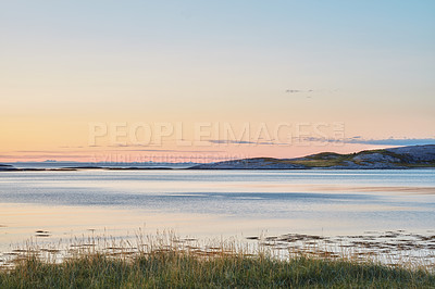 Buy stock photo Beautiful landscape of a mountain near the sea during sunset with copy space. Scenic view of the ocean with golden yellow sunlight at sunrise and copy space. Peaceful coastal bay during sunset