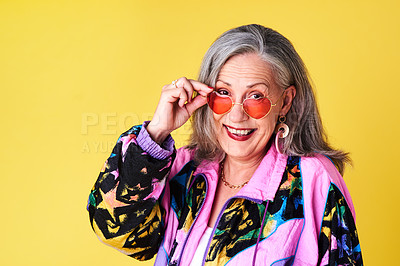 Buy stock photo Portrait of a confident and stylish senior woman wearing sunglasses posing against a yellow background