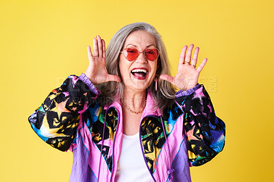 Buy stock photo Cropped shot of a confident and stylish senior woman wearing sunglasses posing against a yellow background