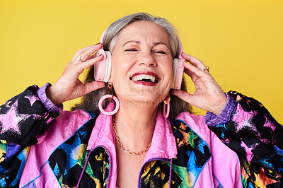 Buy stock photo Cropped shot of a cheerful and stylish senior woman listening to music on headphones against a yellow background
