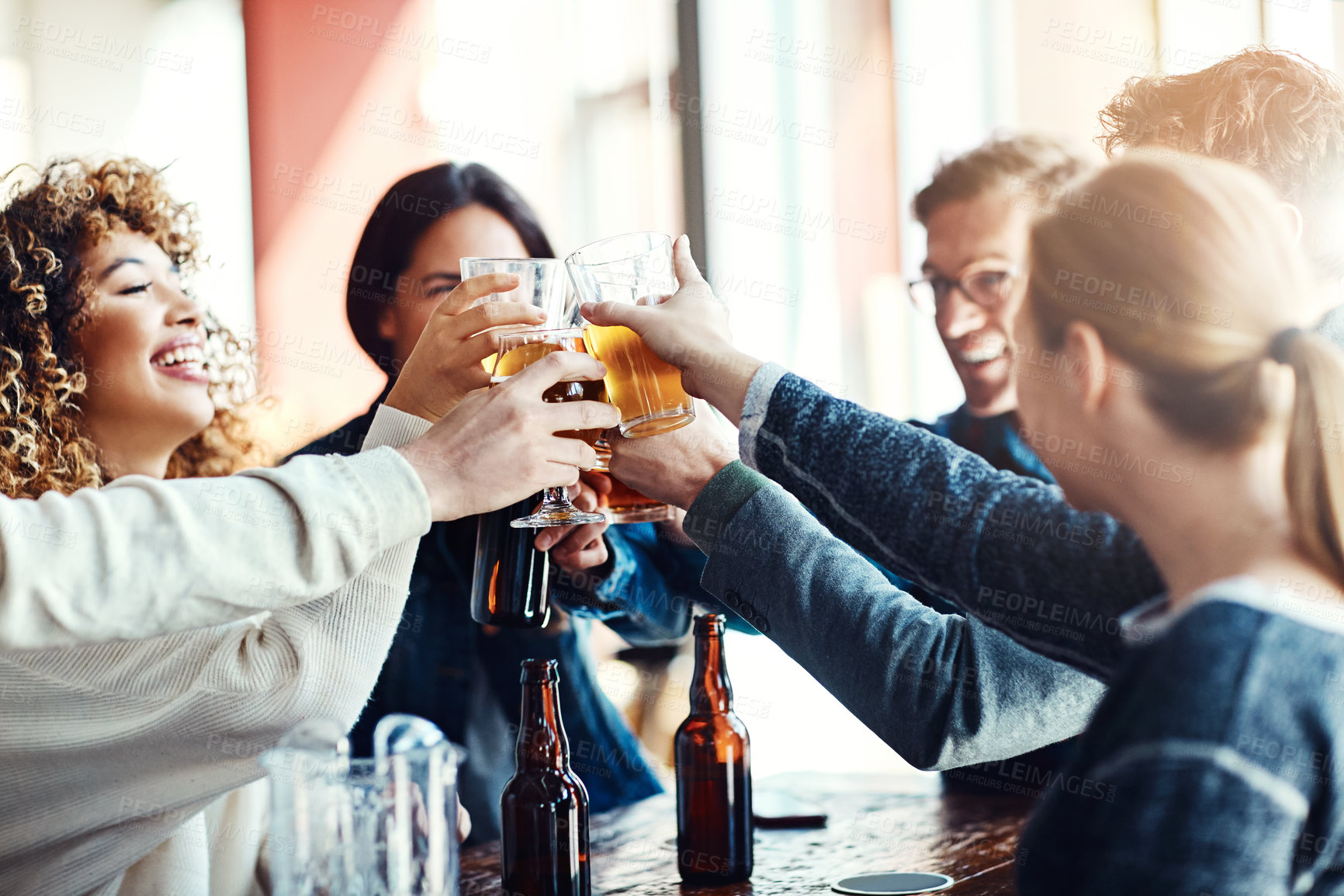 Buy stock photo Shot of a group of happy friends toasting with beers at a bar