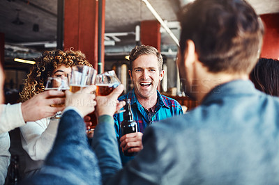 Buy stock photo Shot of a group of happy friends toasting with beers at a bar