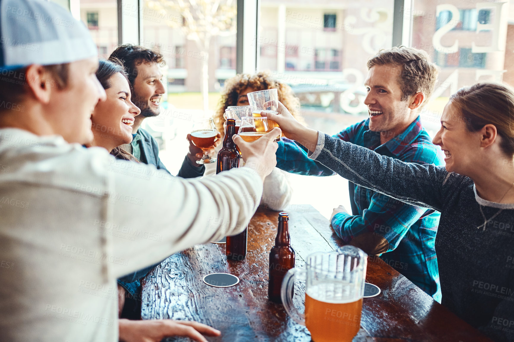 Buy stock photo Shot of a group of happy friends toasting with beers at a bar