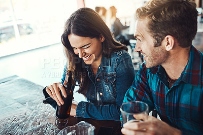 Buy stock photo Shot of a happy young man and woman having beers at a bar