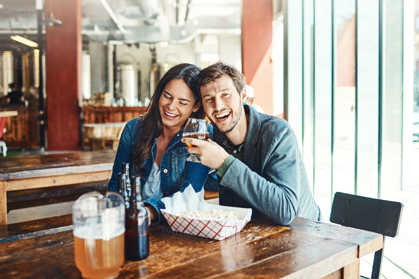 Buy stock photo Shot of a happy young man and woman having beers at a bar