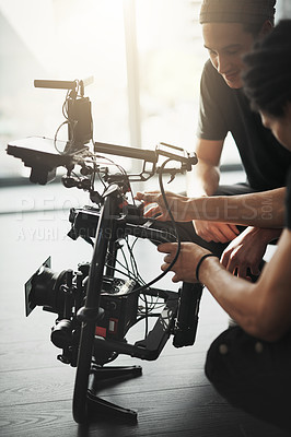 Buy stock photo Behind the scenes shot of two young camera operators shooting a scene with a state of the art camera inside of a studio during the day