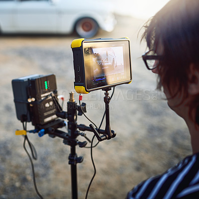 Buy stock photo Over the shoulder shot of a focused young man shooting a scene with a state of the art video camera outside on a beach during the day
