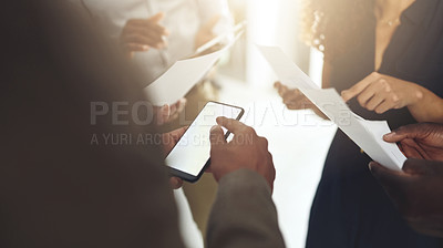 Buy stock photo Shot of a group of businesspeople using digital devices and going through paperwork in an office