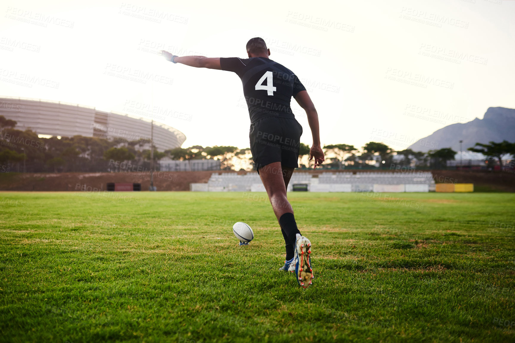 Buy stock photo Full length shot of an unrecognizable sportsman kicking a rugby ball during an early morning training session