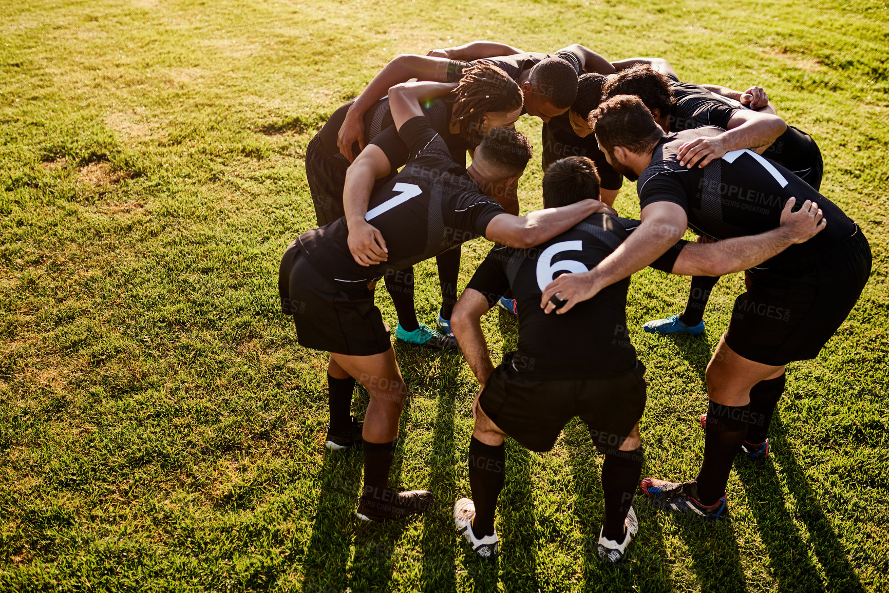 Buy stock photo Full length shot of a diverse group of sportsmen huddled together before playing rugby during the day