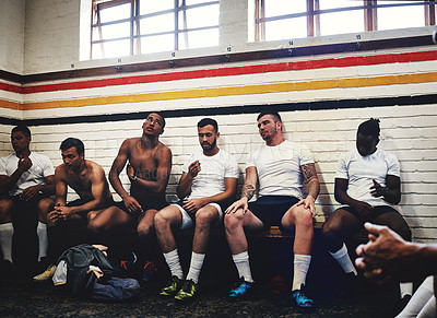 Buy stock photo Cropped shot of a group of handsome young rugby players sitting together in a locker room during the day