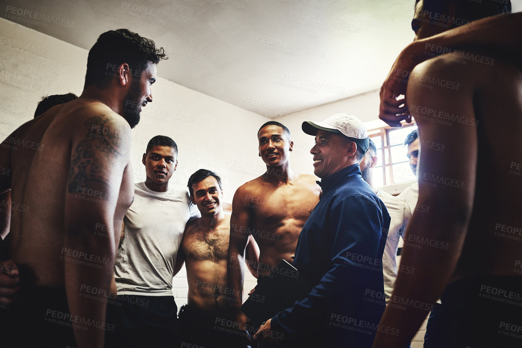 Buy stock photo Cropped shot of a rugby coach addressing his team players in a locker room during the day