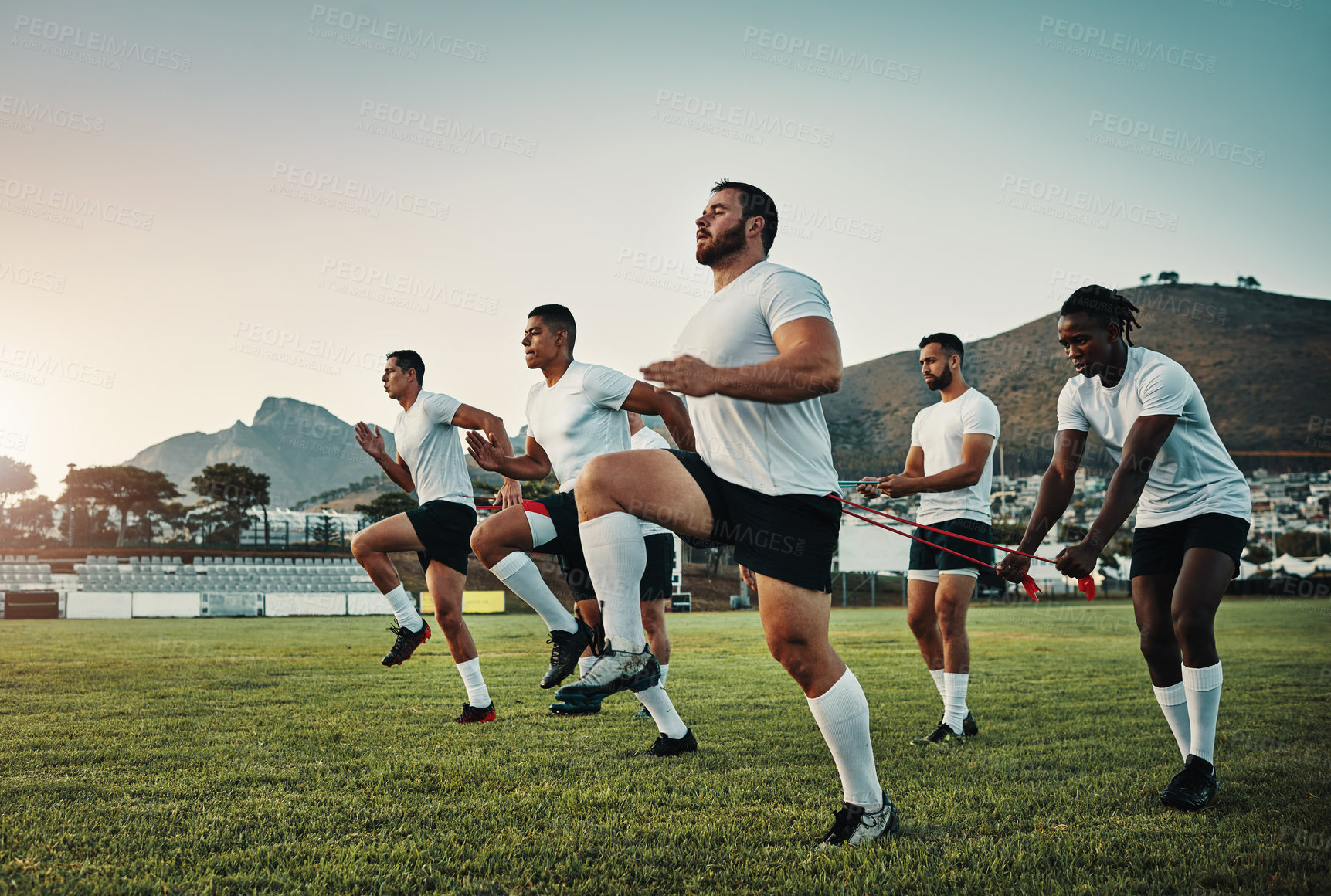 Buy stock photo Full length shot of a group of young rugby players training with bands on the field during the day