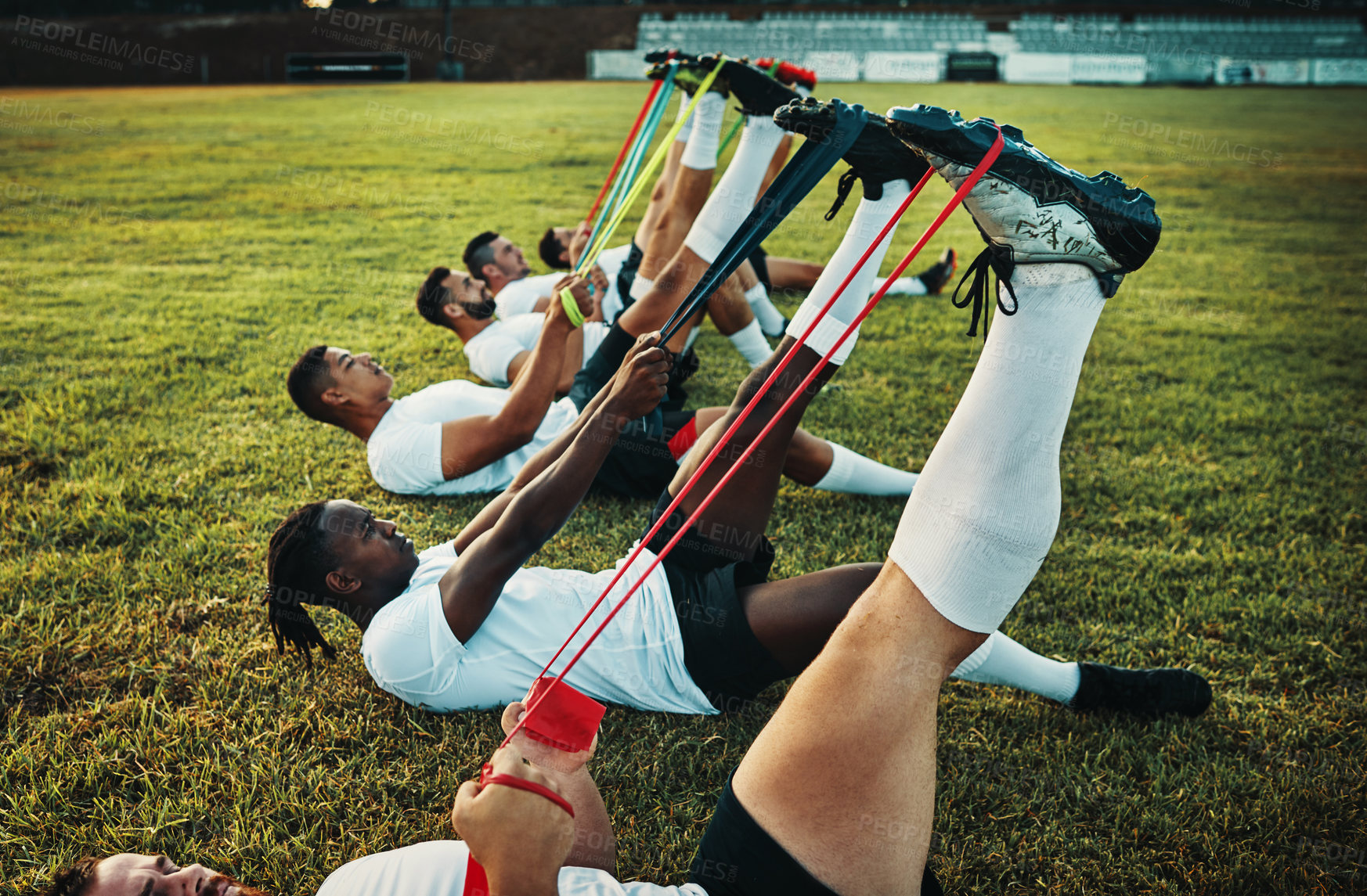 Buy stock photo Cropped shot of a group of young rugby players training with bands on the field during the day