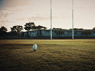 Buy stock photo Still life shot of a rugby ball on an empty rugby field during the early hours of the morning at a sports club