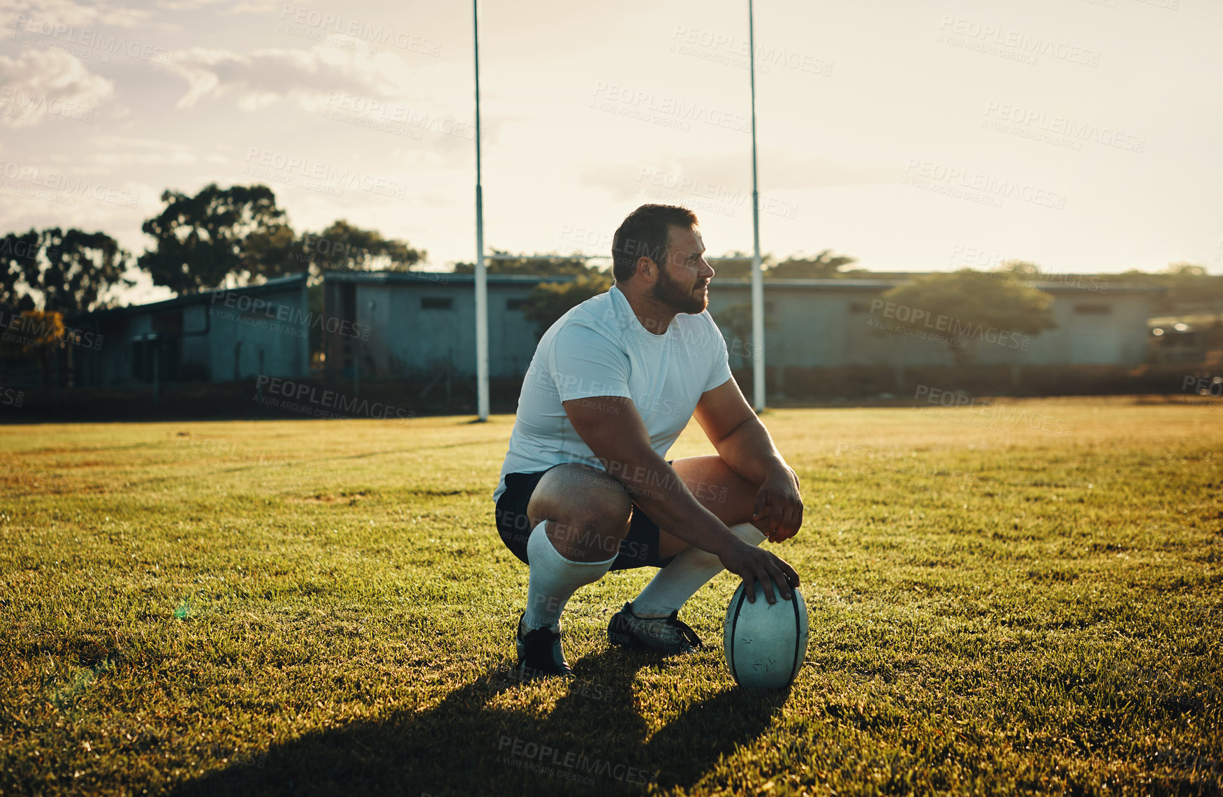 Buy stock photo Full length shot of a handsome young rugby player crouching on the field during the day