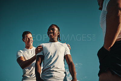 Buy stock photo Low angle shot of two handsome young rugby players smiling cheerfully while training on the field
