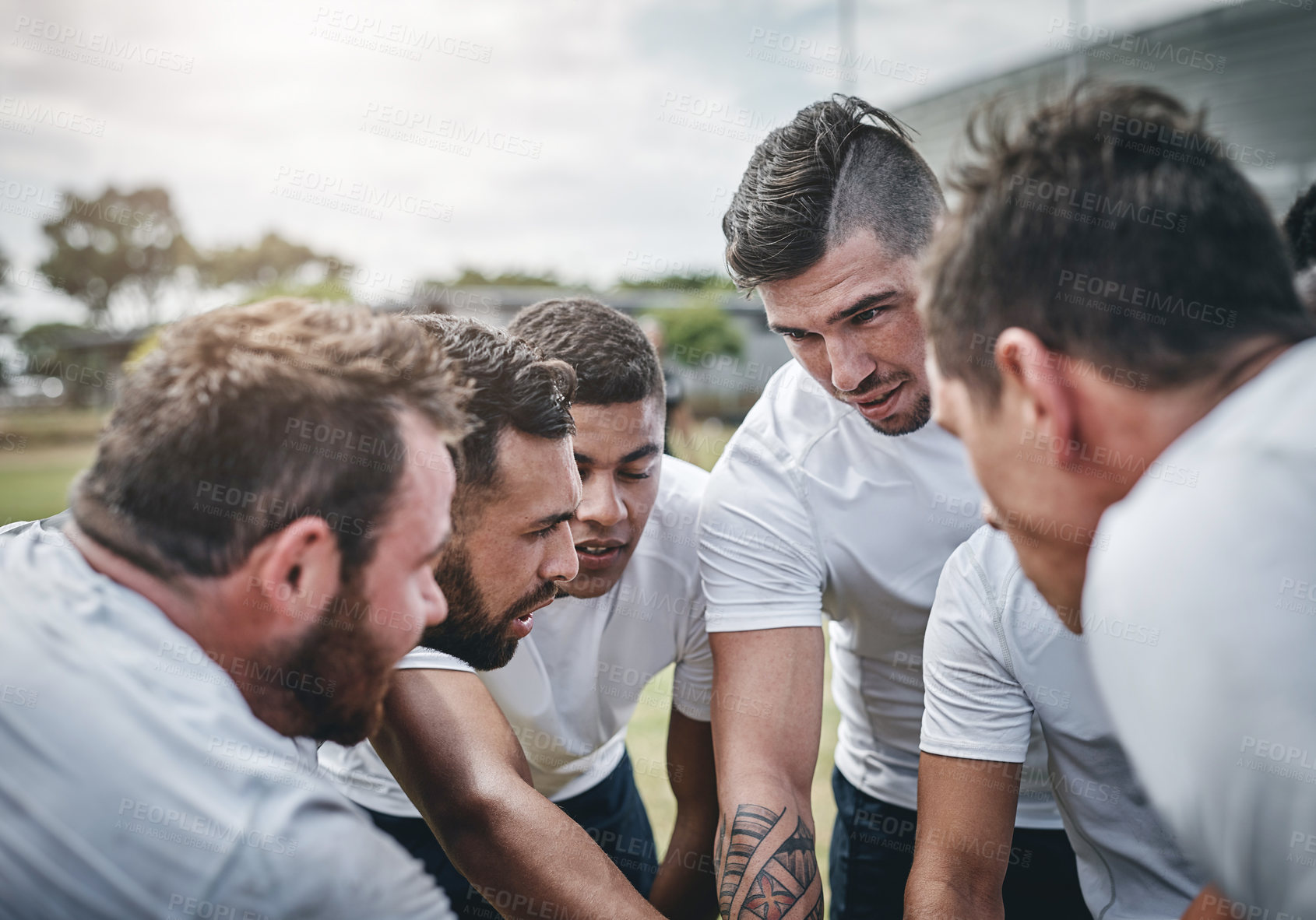 Buy stock photo Cropped shot of a focused young rugby team forming a huddle before a match outside on a rugby field