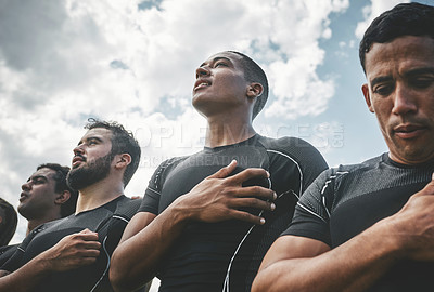 Buy stock photo Cropped shot of a team of confident young rugby players standing at attention singing their anthem outside on a field before a rugby match