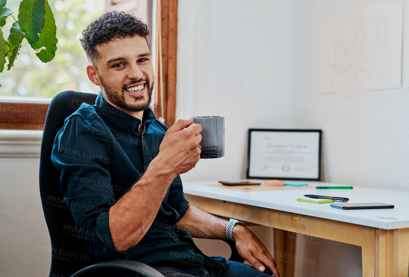 Buy stock photo Shot of a young businessman having a coffee break at his desk in a modern office