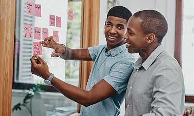 Buy stock photo Shot of two young young businessmen having a brainstorming session in a modern office