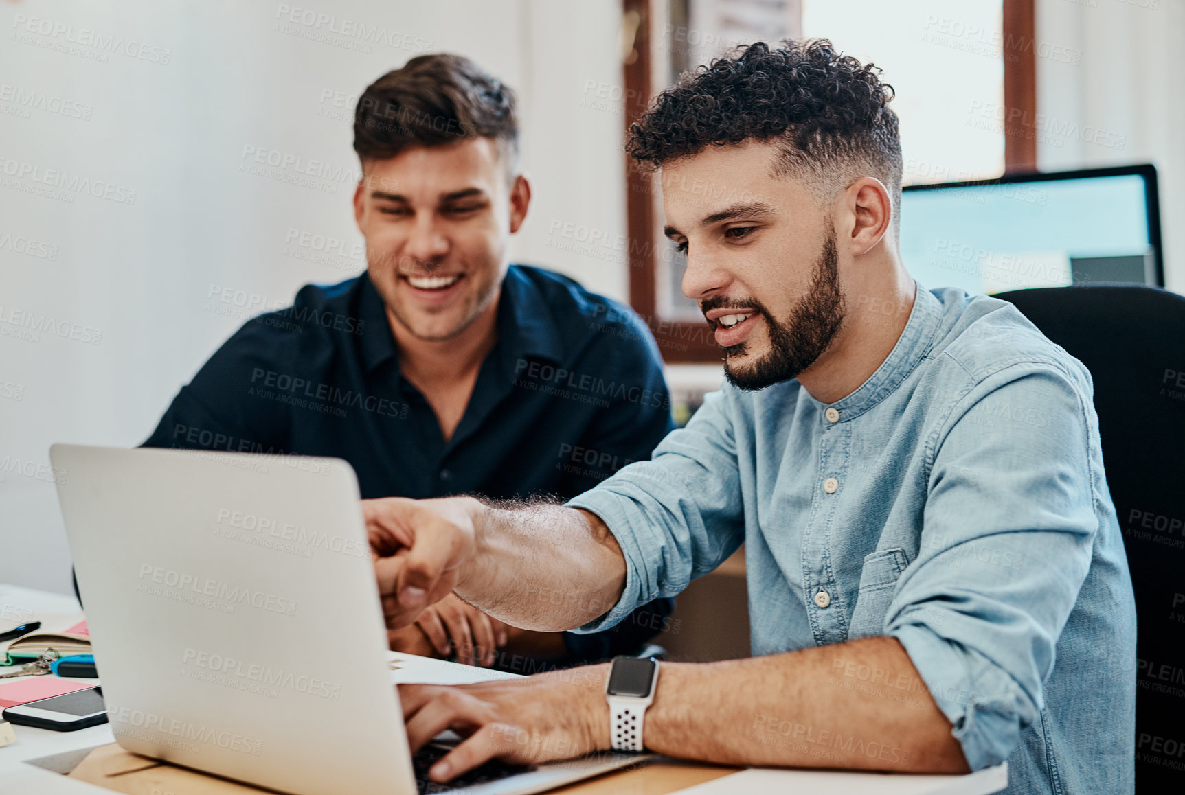 Buy stock photo Shot of two young businessmen using a laptop together in a modern office