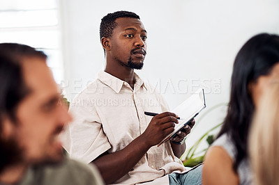 Buy stock photo Shot of a young businessman writing notes during a conference