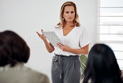 Buy stock photo Shot of a mature businesswoman using a digital tablet while speaking at a conference