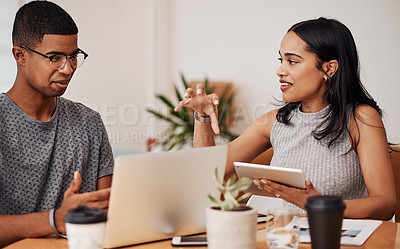 Buy stock photo Shot of two businesspeople using a laptop and digital tablet while working together in an office