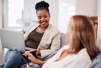 Buy stock photo Cropped shot of two attractive young businesswomen sitting in the office together and using technology during a discussion